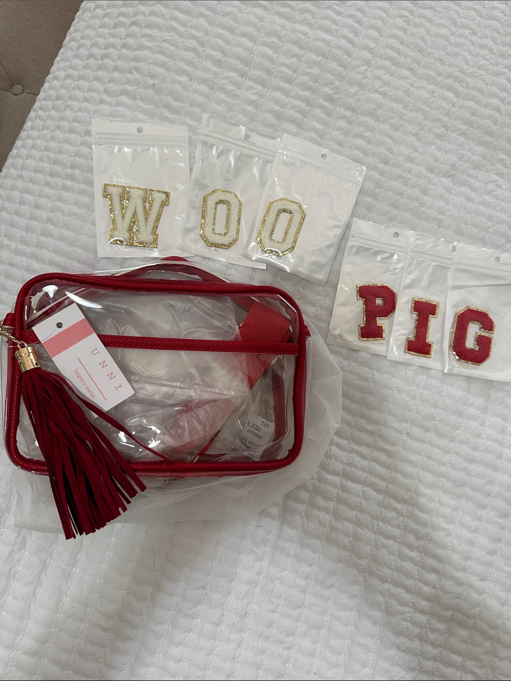 Red and clear game day bag with strap and gold zipper.